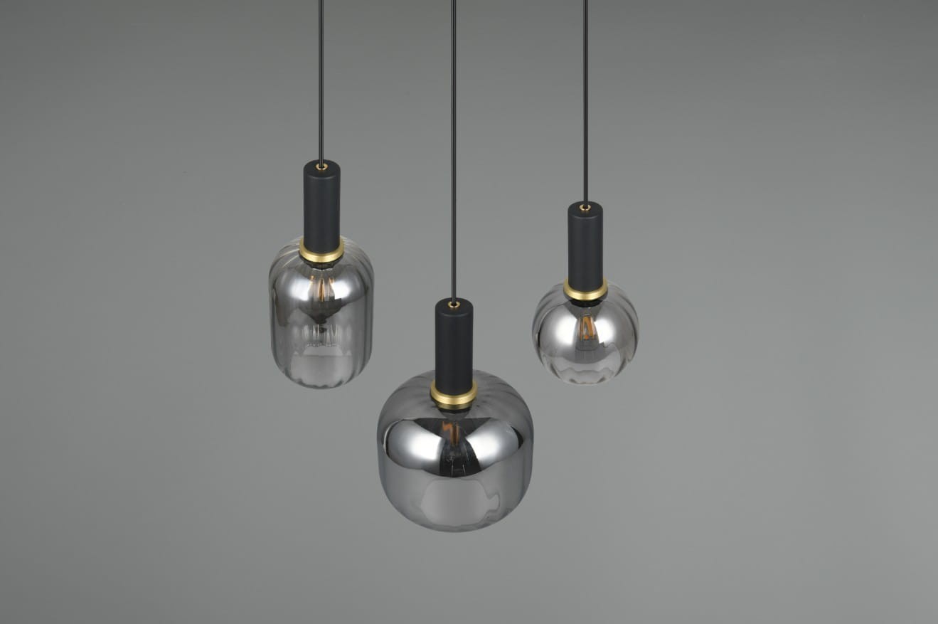 Lampa wisząca Diva z trzema kloszami w kolorze czarnym i chromowanym, z metalowymi uchwytami. Klosze mają różne kształty: cylindryczny, owalny i kulisty. Całość zawieszona na cienkich, czarnych przewodach, na jednolitym, szarym tle.