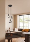 Lampa wisząca Diva w kolorze czarnym i chromowanym z trzema kloszami E27, zawieszona na długich przewodach. Widoczna w nowoczesnym wnętrzu z jasnymi ścianami, dużym oknem i meblami w odcieniach szarości oraz brązu.