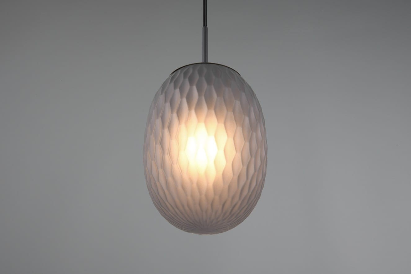 Lampa wisząca Facette w kolorze czarnym z przydymionym kloszem o strukturze wytłaczanej. Klosz ma owalny kształt, zawieszony na cienkim kablu. Źródło światła E27 widoczne wewnątrz klosza, oferujące ciepłe, rozproszone światło.