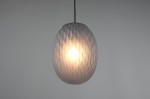 Lampa wisząca Facette w kolorze czarnym z przydymionym kloszem o strukturze wytłaczanej. Klosz ma owalny kształt, zawieszony na cienkim kablu. Źródło światła E27 widoczne wewnątrz klosza, oferujące ciepłe, rozproszone światło.