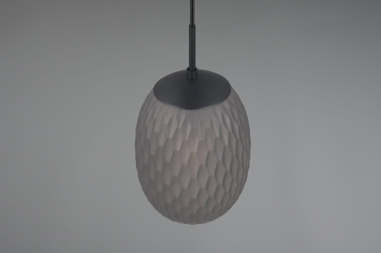 Lampa wisząca Facette 1xE27 w kolorze czarnym z przydymionym kloszem, o owalnym kształcie z fakturą w formie sześciokątów. Ujęcie z góry, produkt zawieszony na cienkim kablu, na jednolitym, jasnym tle.