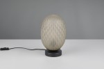 Lampa stołowa Facette z kloszem w kształcie owalnym, pokrytym strukturą w formie rombów, w kolorze mlecznobiałym, osadzona na czarnej, okrągłej podstawie. Widoczny kabel z włącznikiem. Ujęcie frontalne.