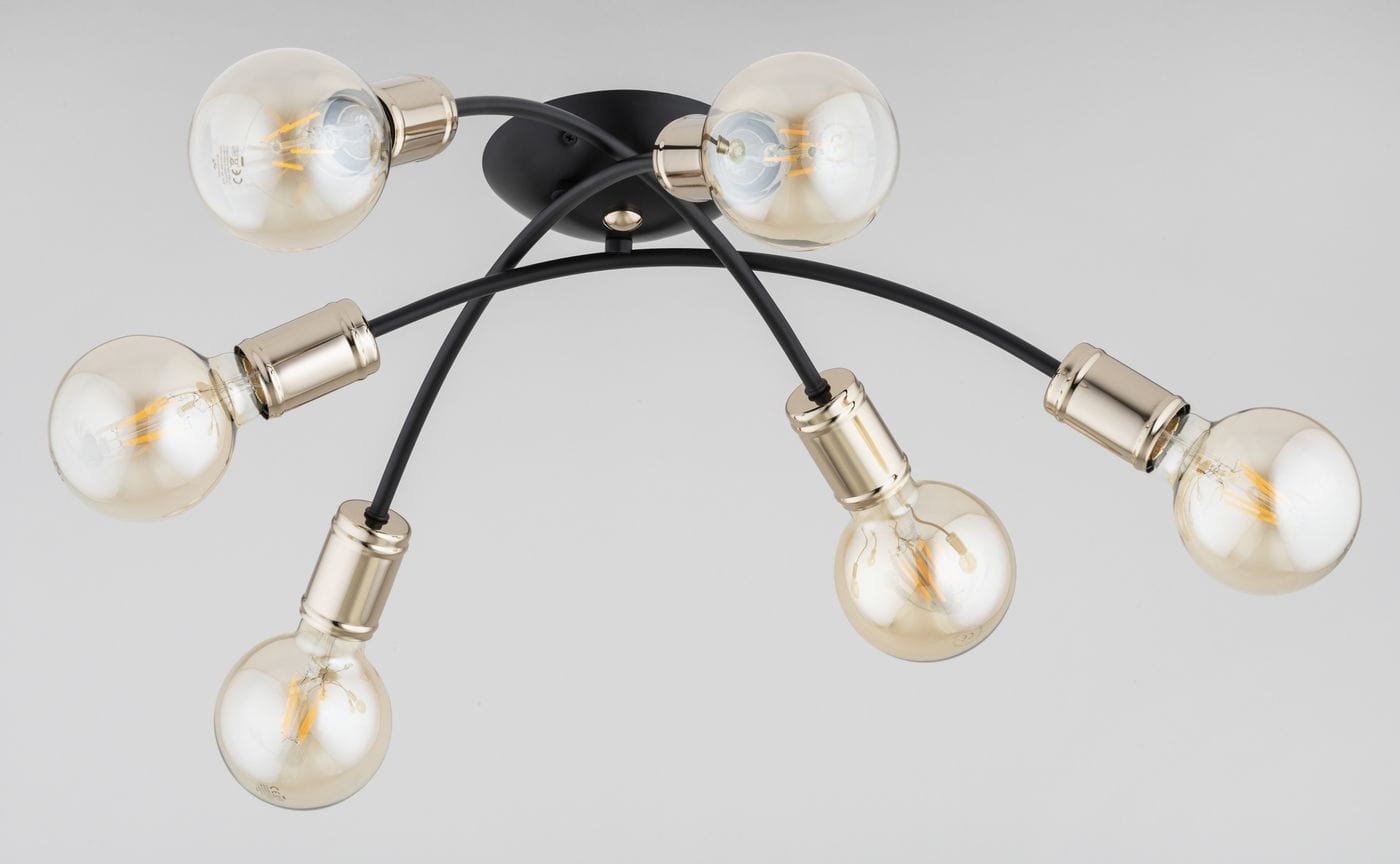 Lampa sufitowa Sedna z sześcioma oprawami E27, czarno-złota. Posiada zaokrąglone klosze w przezroczystym kolorze, umocowane na zakrzywionych, czarnych przewodach. Montowana na okrągłej podstawie, widoczna elegancka metaliczna wykończenie.