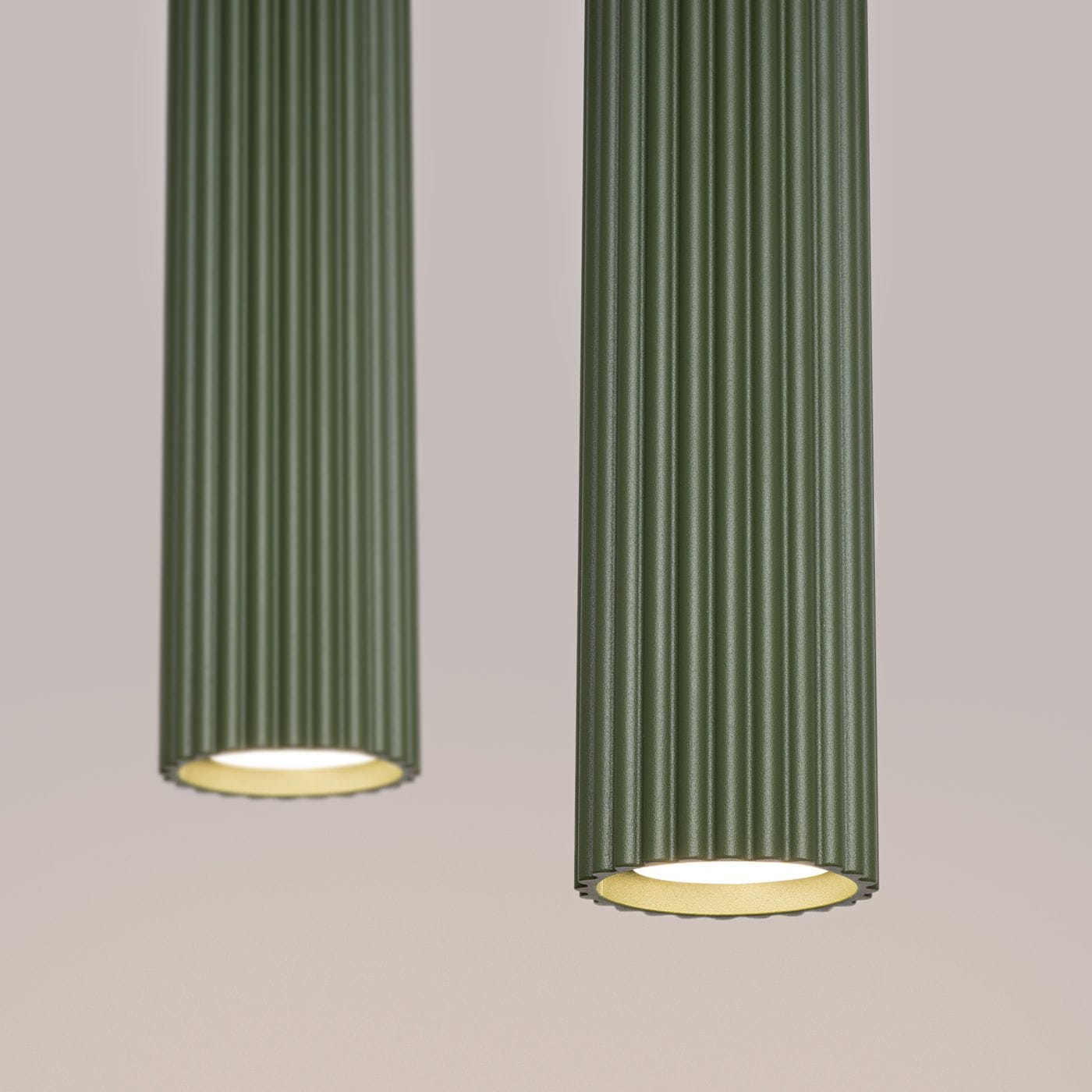 Lampa wisząca Karbon 2 w kolorze oliwkowym z dwoma cylindrycznymi kloszami z rowkowanej tekstury. Ujęcie z bliska, ukazujące detale wykończenia oraz otwarte dolne części kloszy z żarówkami GU10. Tło w neutralnym odcieniu.