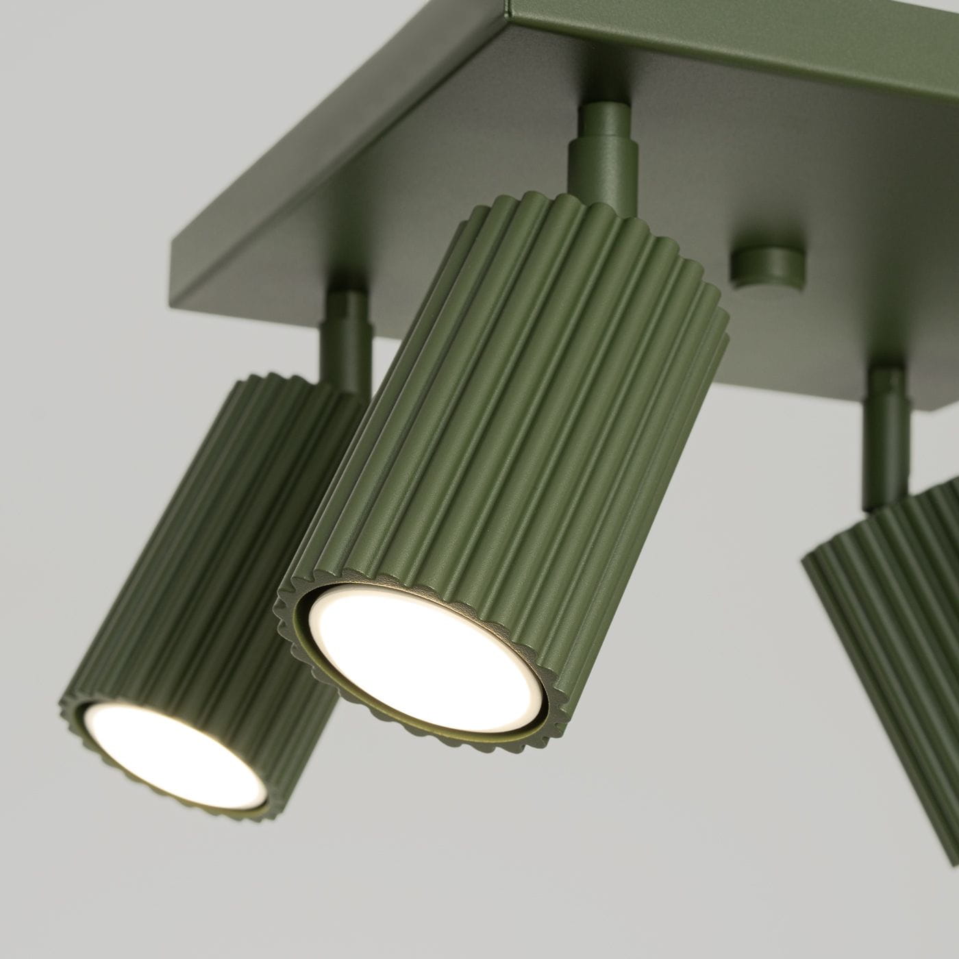 Lampa sufitowa Karbon L w kolorze oliwkowym, z czterema reflektorami GU10. Reflektory mają żebrowaną fakturę i są zamontowane na prostokątnej, matowej podstawie. Ujęcie z dołu, ukazujące detale i kształt lampy.