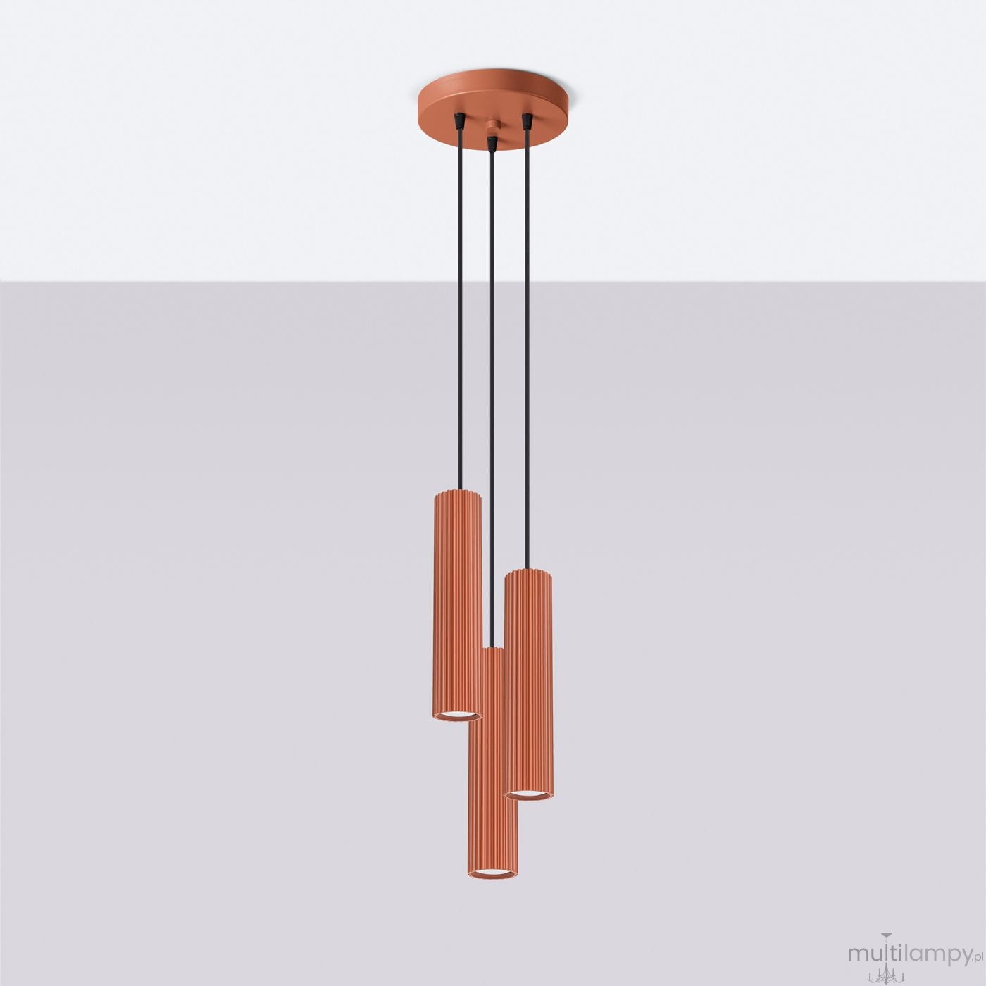 Lampa wisząca Karbon 3P w kolorze ochra czerwona z trzema cylindrycznymi kloszami z rowkowaną fakturą. Zawieszona na czarnych linkach z okrągłym mocowaniem na suficie. Klosze przystosowane do żarówek GU10.