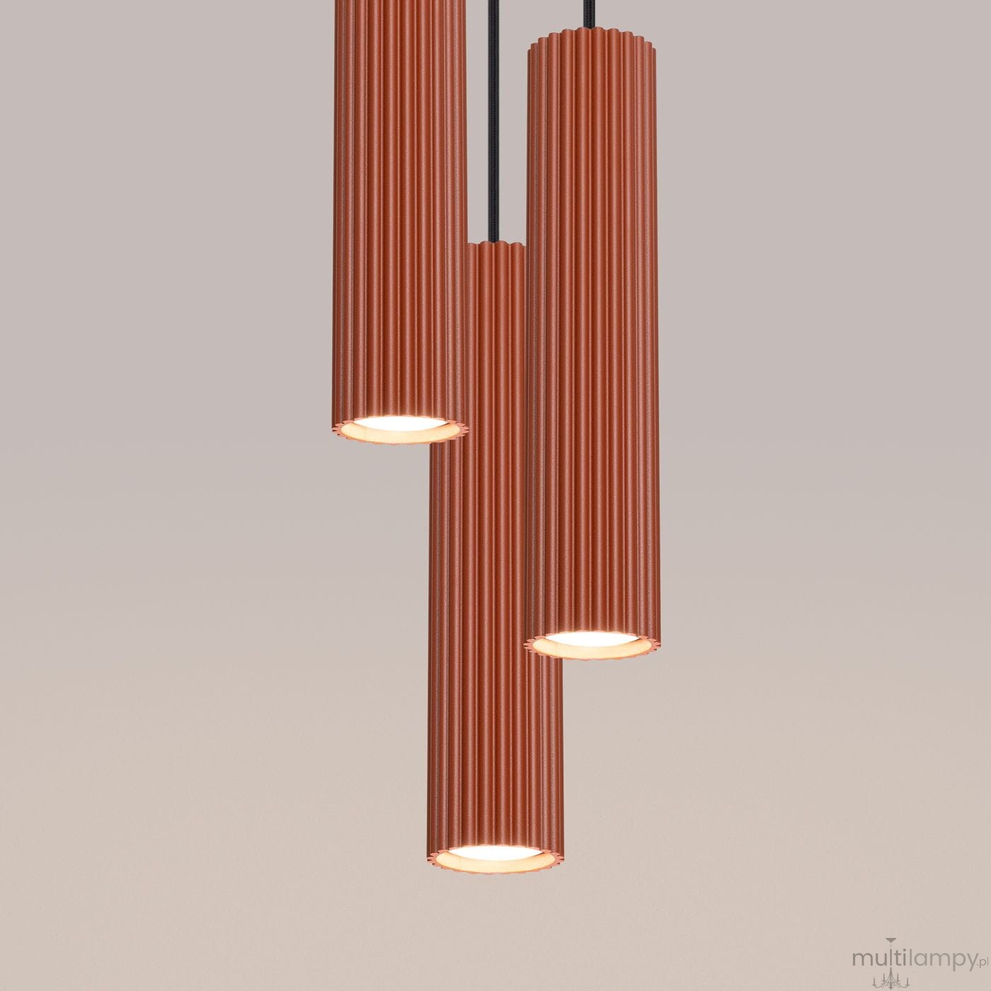 Lampa wisząca Karbon 3P w kolorze ochra czerwona z trzema cylindrycznymi kloszami o żebrowanej fakturze. Ujęcie frontalne, klosze zawieszone na czarnych przewodach, z widocznymi źródłami światła GU10. Tło w jednolitym odcieniu.