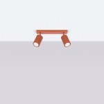 Lampa sufitowa Karbon (spot) 2xGU10 w kolorze ochra czerwona. Posiada dwa cylindryczne klosze z rowkowaną fakturą, zamontowane na prostokątnej podstawie. Ujęcie frontalne, tło w jasnym odcieniu.