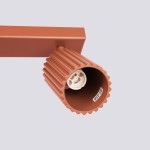 Karbon lampa sufitowa (spot) 3xGU10 w kolorze ochra czerwona, z cylindrycznym kloszem o żłobionej fakturze. Ujęcie z boku, pokazujące gniazdo na żarówkę GU10. Prosta konstrukcja, zamontowana na prostokątnej podstawie w jednolitym tle.
