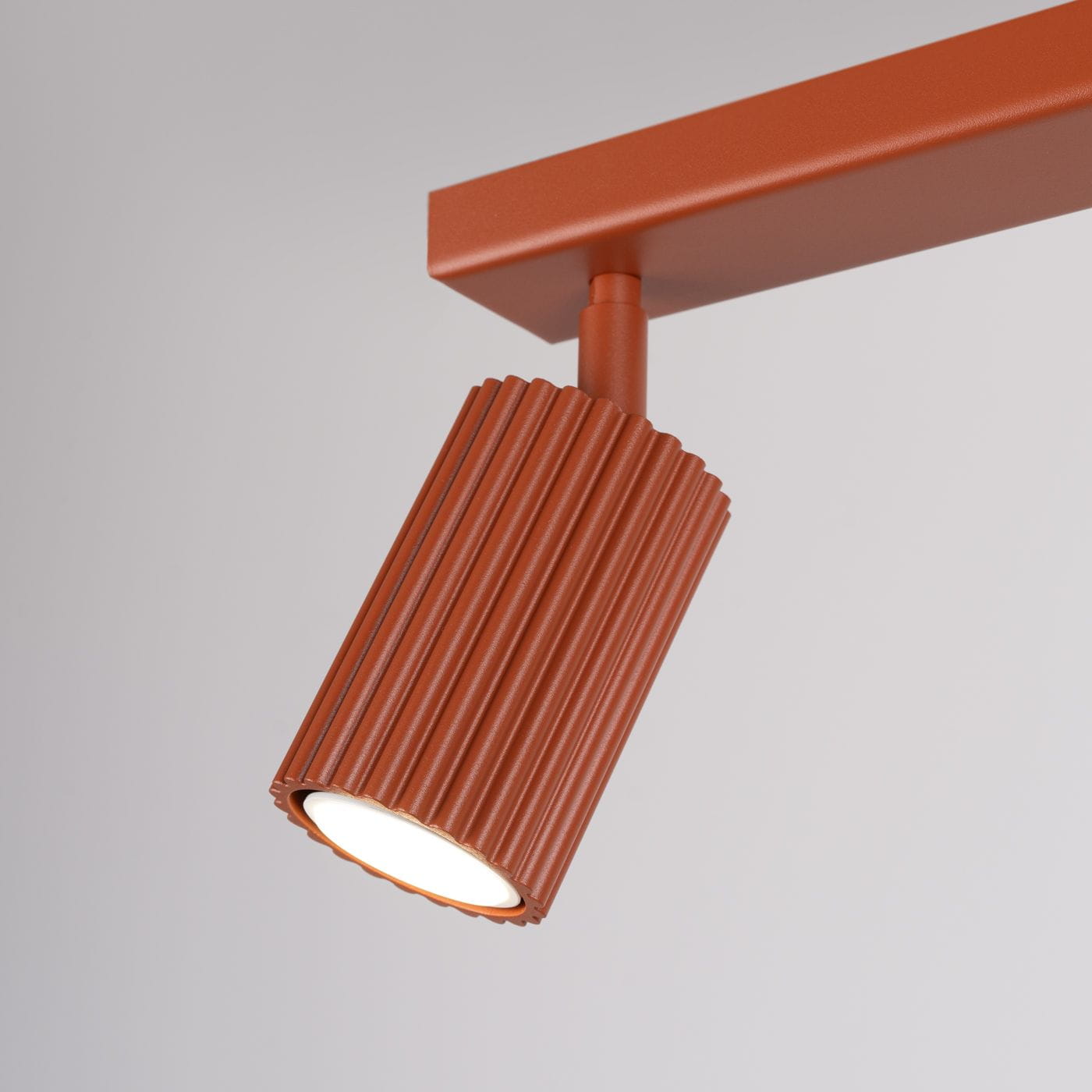 Karbon lampa sufitowa (spot) 3xGU10 w kolorze ochra czerwona, z cylindrycznym kloszem o żłobionej fakturze, zamontowana na prostokątnej podstawie. Ujęcie z boku, prezentujące detal klosza i jego oświetlenie.