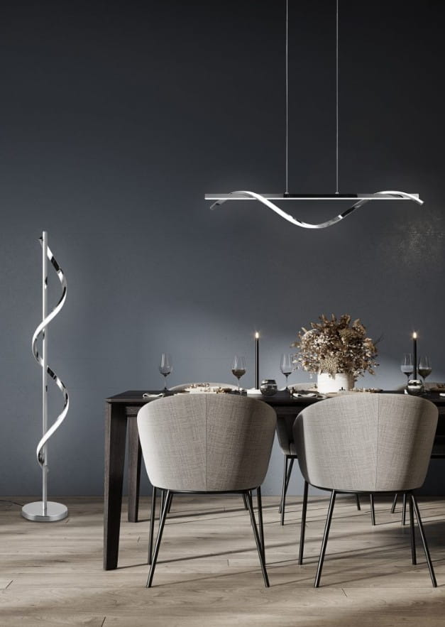 Isabel LED lampa wisząca 2-punktowa w chromie, o nowoczesnym designie, z delikatnymi, falującymi kształtami. Powieszona nad drewnianym stołem w stylowej jadalni, na tle ciemnej ściany, obok eleganckich, szarych krzeseł.