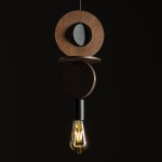Lampa wisząca Drops Wood C z jednym gniazdem E27. Składa się z okrągłych elementów z ciemnego drewna oraz czarnego detalu. W dolnej części umieszczona żarówka o vintage''owym kształcie. Produkt zawieszony na cienkim przewodzie, na jednolitym ciemnym tle.