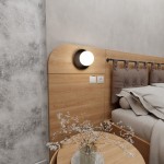 Minerva kinkiet 1-punktowy w kolorze czarnym, zamontowany na ścianie obok łóżka. Okrągła lampa z białym kloszem, otoczona czarną oprawą. W tle drewniana ściana i jasne pościele, stół z wazonem i kwiatami.