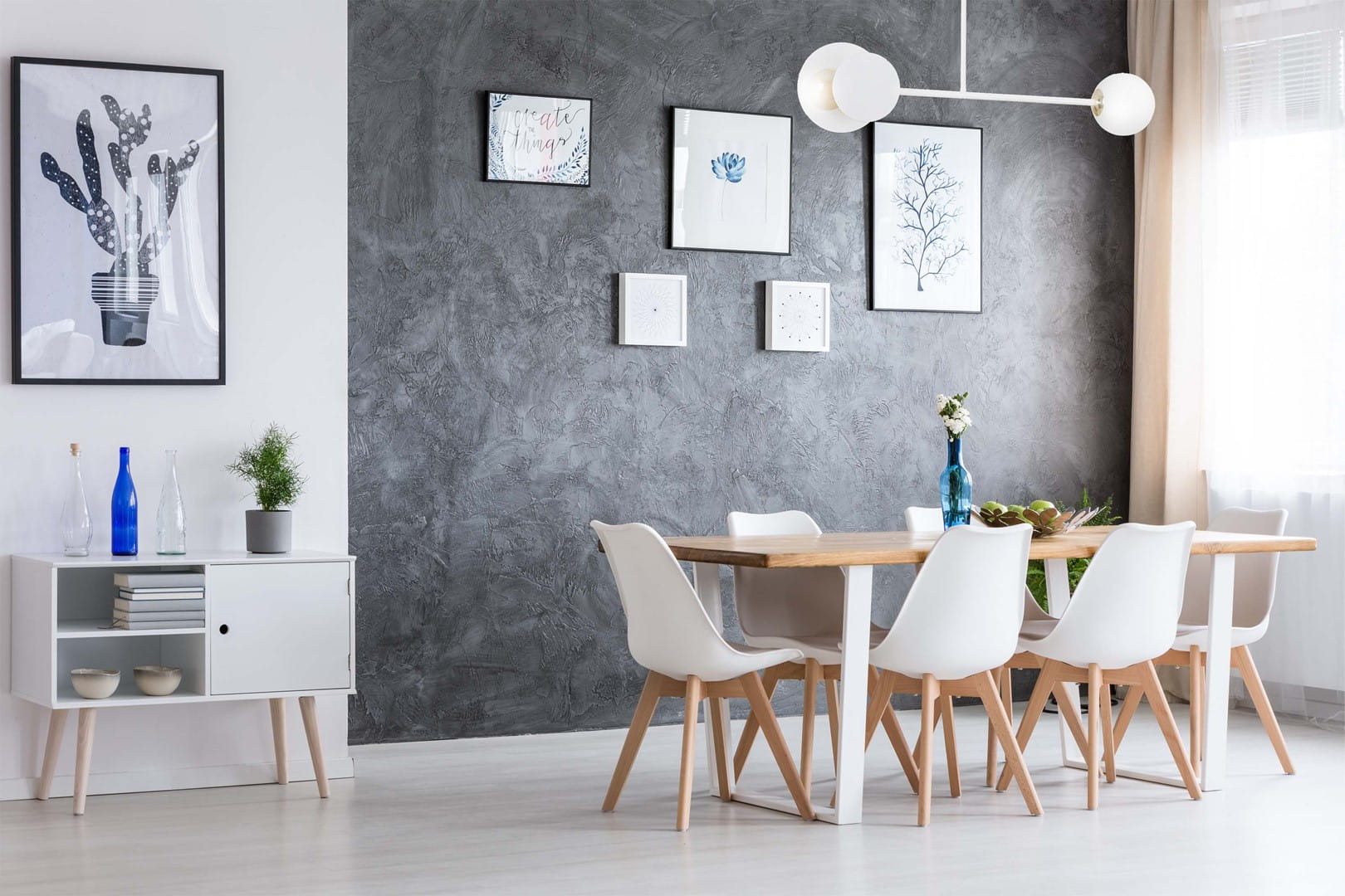 Lampa sufitowa Minerva 2-punktowa w kolorze białym, z dwoma okrągłymi kloszami umieszczonymi na długim, prostym ramieniu. Produkt zamontowany na suficie w nowoczesnym wnętrzu, z widocznym drewnianym stołem i białymi krzesłami. Tło w odcieniach szarości.