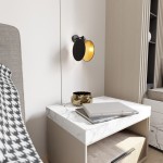 Kinkiet Motif 1xE14 w kolorze czarnym i złotym, montowany na ścianie obok łóżka. Okrągła lampa z czarną obudową i złotym wnętrzem, umieszczona nad stolikiem nocnym z marmurowym blatem. Widoczne książki i dekoracyjny pojemnik na stoliku.