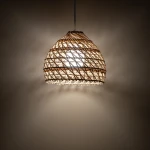 Lampa wisząca Boho S z białym kloszem z rattanu, o kształcie przypominającym kulę, zawieszona na cienkim przewodzie. Wewnątrz znajduje się żarówka E27, emitująca ciepłe światło, które rzuca delikatny cień na ścianę.