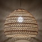 Lampa wisząca Boho L z białego rattanowego materiału, o zaokrąglonym kształcie, z widoczną żarówką E27 w środku. Zawieszona na cienkim przewodzie, tworzy delikatne cienie na ścianie. Idealna do wnętrz w stylu boho.