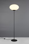 Lampa podłogowa Fomento w kolorze czarnym i białym, z okrągłym, białym kloszem. Stojąca, z metalową podstawą i smukłym stelażem. Widoczny przewód z wtyczką na podłodze. Ujęcie frontalne na jednolitym tle.