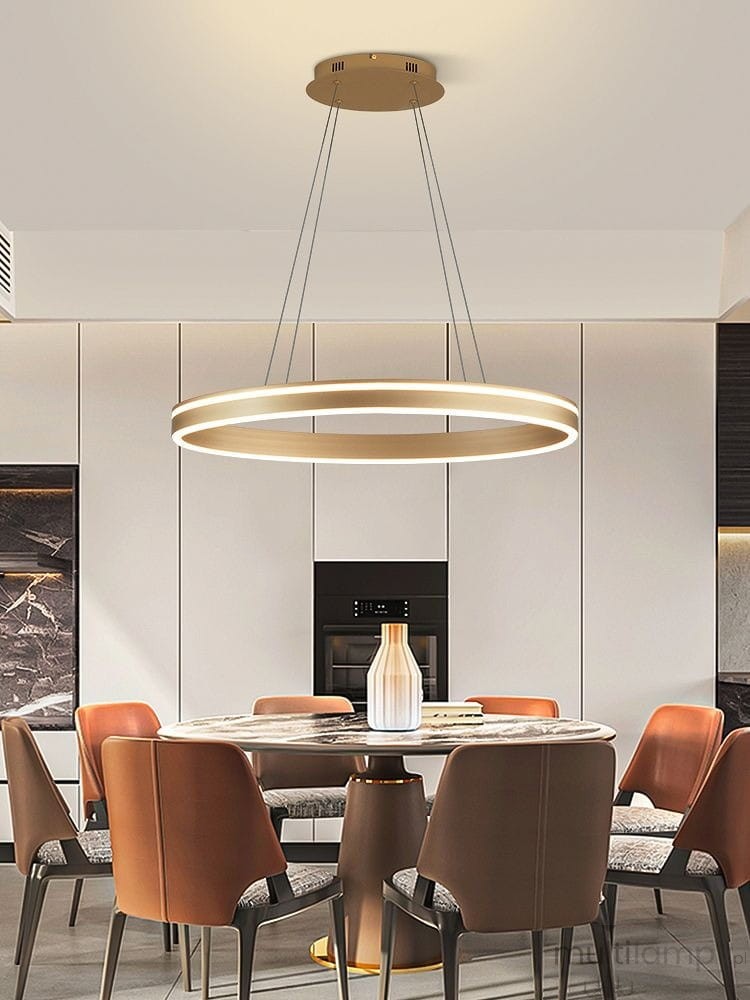 Lampa wisząca Vivies 1xLED/36W w kolorze złotym, o okrągłym kształcie, zawieszona na cienkich linkach. Widoczna w kuchni nad okrągłym stołem, w jasnym otoczeniu z nowoczesnymi meblami.