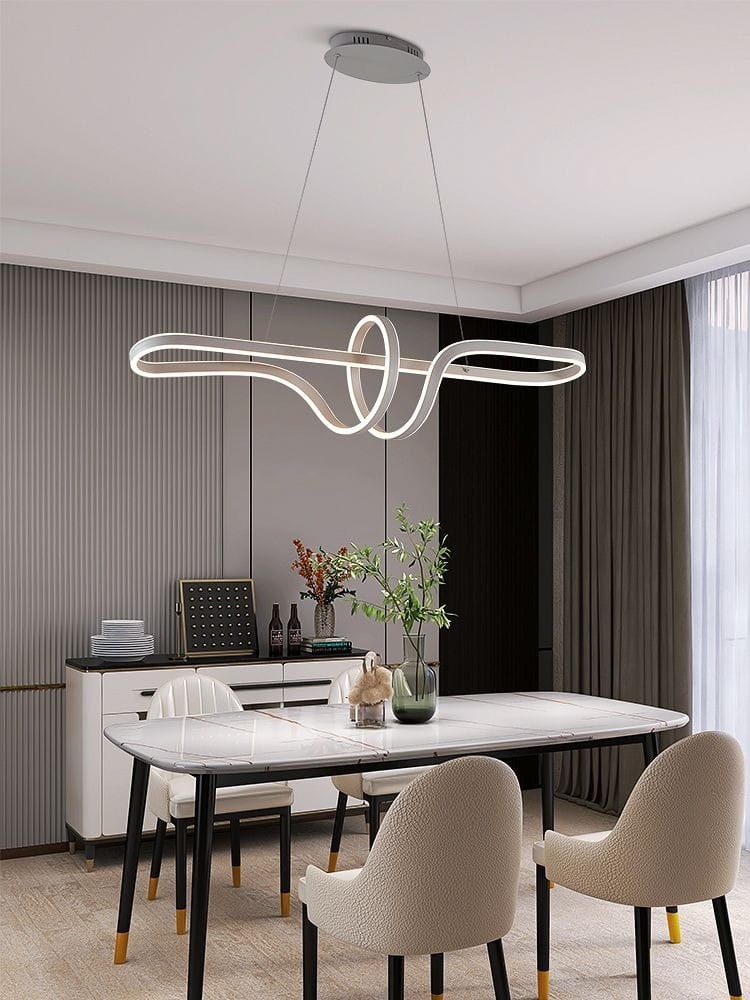 Lampa wisząca Trevance 1xLED/72W w kolorze szarym, o nowoczesnym, organicznym kształcie, zawieszona nad stołem w eleganckiej jadalni. W tle widoczne elementy wystroju, takie jak stół z marmurowym blatem i krzesła tapicerowane w jasnym kolorze.