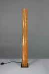 Lampa podłogowa Karuni z czarną podstawą i jasnym drewnem w formie prostokątnego słupa. Widoczne szczeliny w drewnie emitujące światło. Ułożona w pionie, na gładkim tle. Kabel z włącznikiem widoczny obok podstawy.