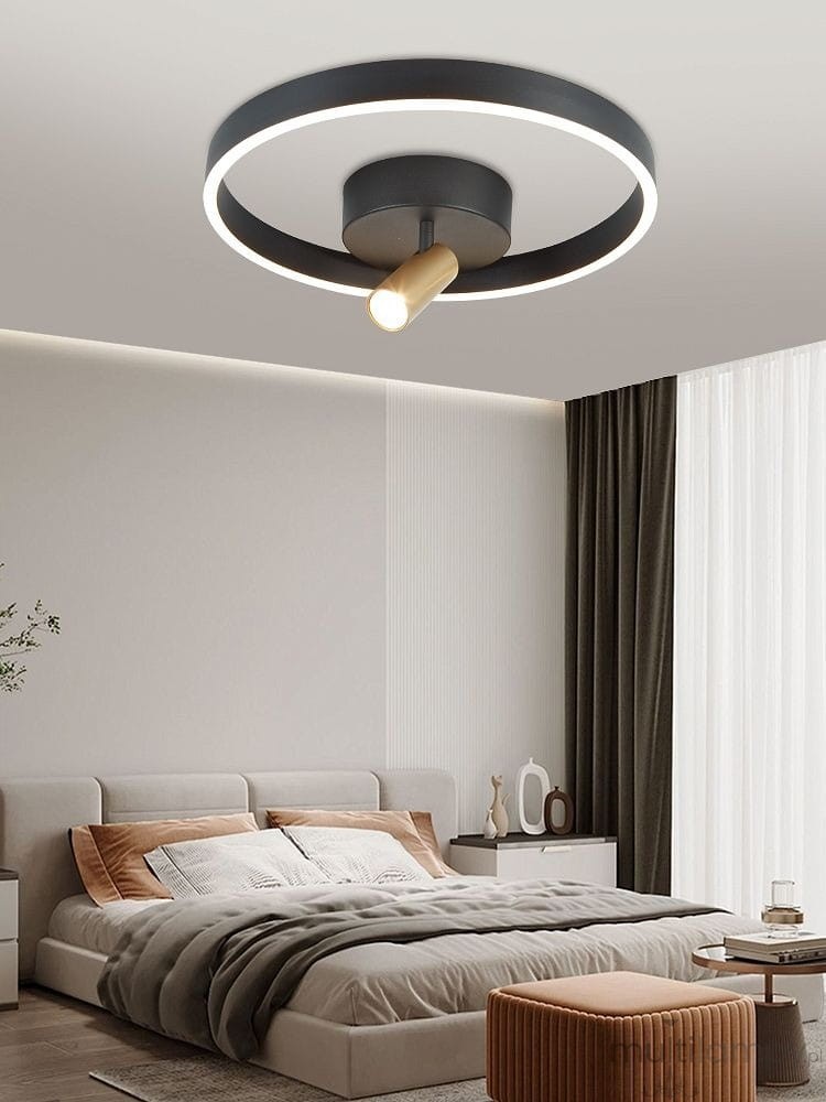 Lampa sufitowa Pignano 2xLED/18W w kolorze czarnym i złotym, z okrągłym korpusem i centralnym źródłem światła. Ujęcie z dołu, montowana na suficie, w nowoczesnym wnętrzu sypialni z jasnymi ścianami i zasłonami.