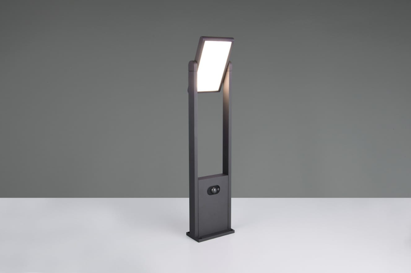Lampa ogrodowa Malawi H61 w kolorze antracytowym, z czujnikiem ruchu. Wysoka, prostokątna konstrukcja z LED 5W, IP65. Ujęcie frontalne, lampa stoi na białym blacie, z włączonym źródłem światła. W dolnej części widoczny czujnik.