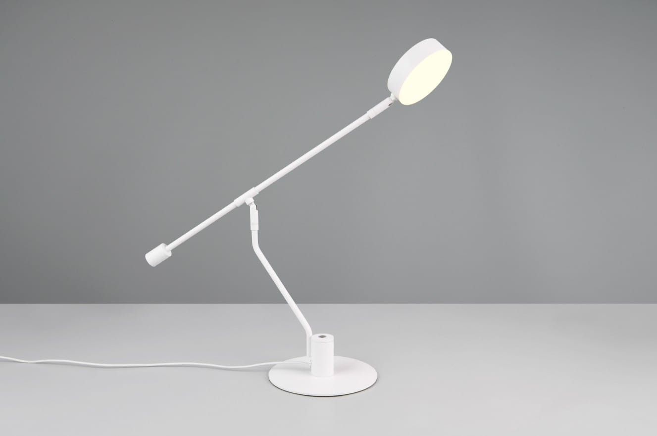 Biała lampa biurkowa Manduro z jedną diodą LED 6W, z regulowanym ramieniem i okrągłą podstawą. Ujęcie z boku, na szarym tle, lampa ustawiona w pozycji stojącej, z wyraźnym źródłem światła w górnej części. Kabel zasilający widoczny na stole.
