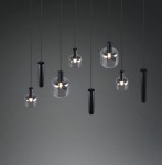 Lampa wisząca Mataro z ośmioma źródłami E27/E14/GU10, w czarnej obudowie, z przezroczystymi kloszami w różnych kształtach. Produkt wisi na cienkich linkach, zróżnicowane wysokości kloszy tworzą nowoczesną aranżację. Tło ciemne.