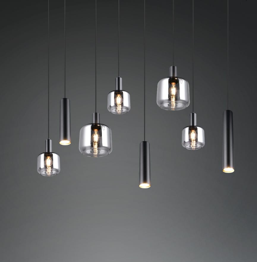 Lampa wisząca Mataro z osiemnastoma źródłami światła E27/E14/GU10, w kolorze czarnym. Składa się z różnych szklanych kloszy w kształcie cylindrów oraz kul, zawieszonych na cienkich linkach, na ciemnym tle.