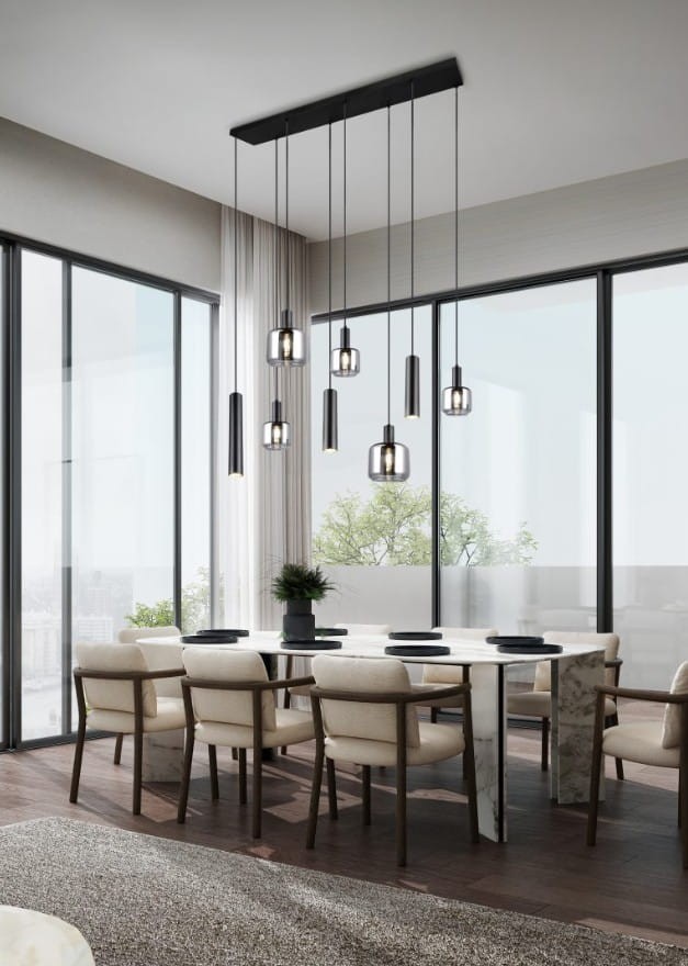 Lampa wisząca Mataro w kolorze czarnym z ośmioma źródłami światła (E27/E14/GU10), zawieszona na długich linkach, umieszczona nad białym stołem w nowoczesnej jadalni z dużymi oknami i roślinnością w tle.