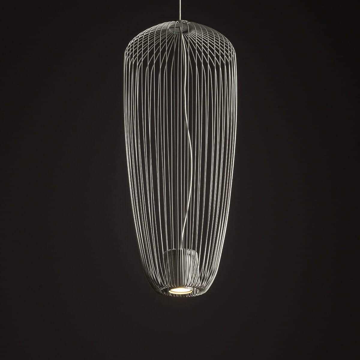 Lampa wisząca Pumpkin S w kolorze jasnoszarym, wykonana z cienkich metalowych prętów, o opływowym kształcie. Widoczny jeden gwint na żarówkę GU10. Zawieszona na cienkim przewodzie, na tle ciemnego tła.