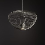 Lampa wisząca Pumpkin M w jasnoszarym kolorze, wykonana z cienkich metalowych drutów, ma okrągły kształt. Widoczny jest gniazdko na żarówkę GU10. Ujęcie z dołu, na jednolitym ciemnym tle, podkreśla nowoczesny design lampy.