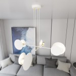 Lampa wisząca Idea 4-punktowa w kolorze białym, z okrągłymi kloszami i złotymi elementami, zawieszona na cienkich linkach. Ujęcie z góry, z widocznym tłem w postaci szarej kanapy i abstrakcyjnego obrazu.
