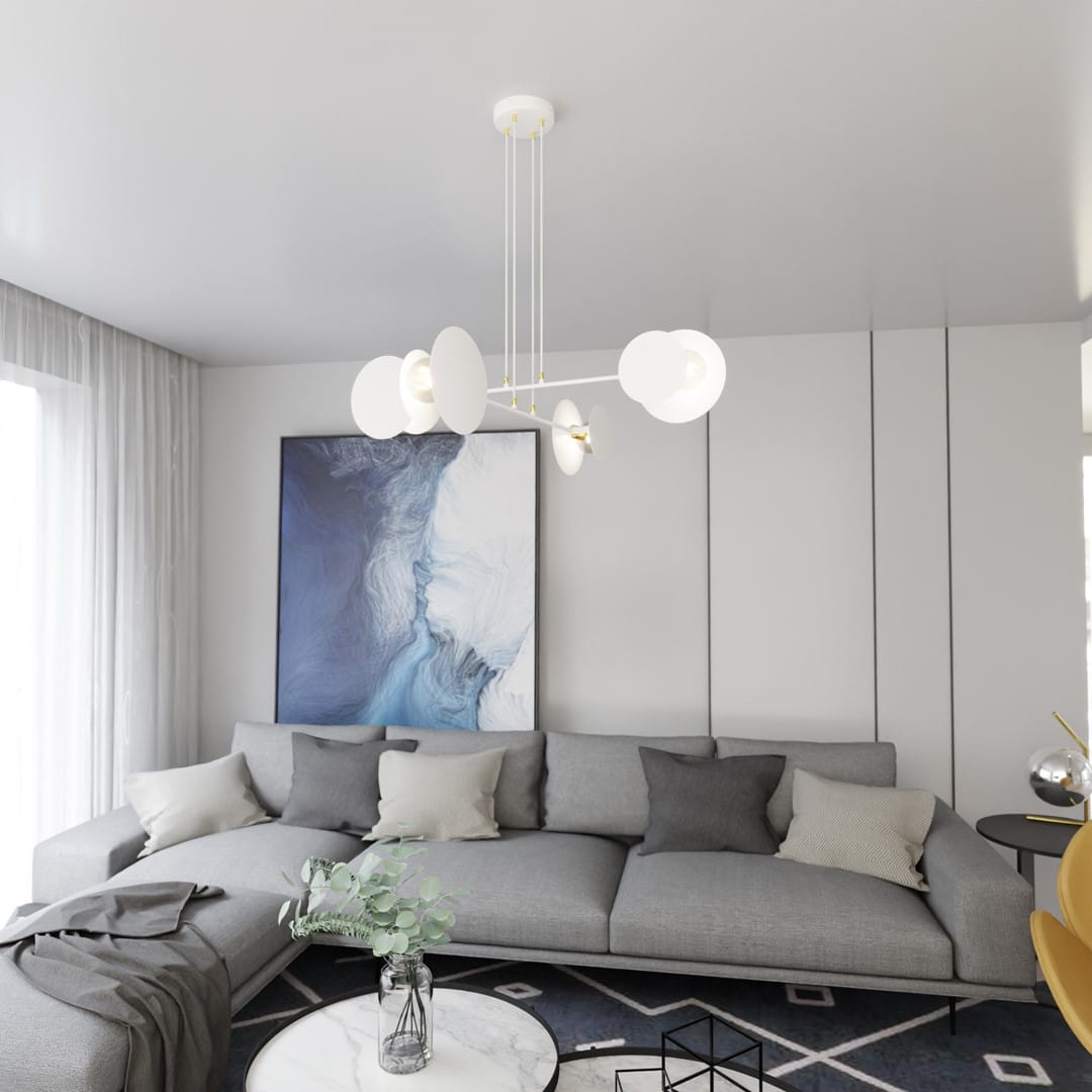 Lampa wisząca Idea 4-punktowa w kolorze białym z pięcioma okrągłymi kloszami, zawieszona na cienkich linkach. W tle nowoczesny salon z szarym narożnikiem i obrazem w odcieniach niebieskiego.
