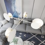 Lampa wisząca Idea 4-punktowa w białym kolorze z okrągłymi kloszami, zawieszona w salonie. Elementy złotej metalowej konstrukcji są widoczne przy każdym z kloszy. Tło stanowi szary narożnik oraz nowoczesny dywan.