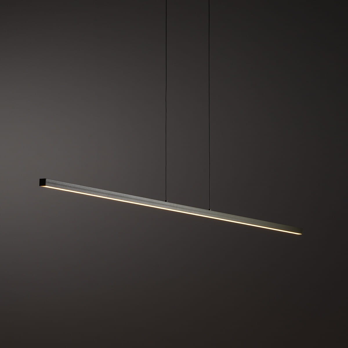 Lampa wisząca Bar L150 w kolorze oliwkowym, z minimalistycznym, prostokątnym kształtem, zawieszona na dwóch cienkich linkach. Źródło światła LED o mocy 32W, temperatura barwowa 3000K, emitujące ciepłe światło. Tło ciemne, podkreślające elegancki design.
