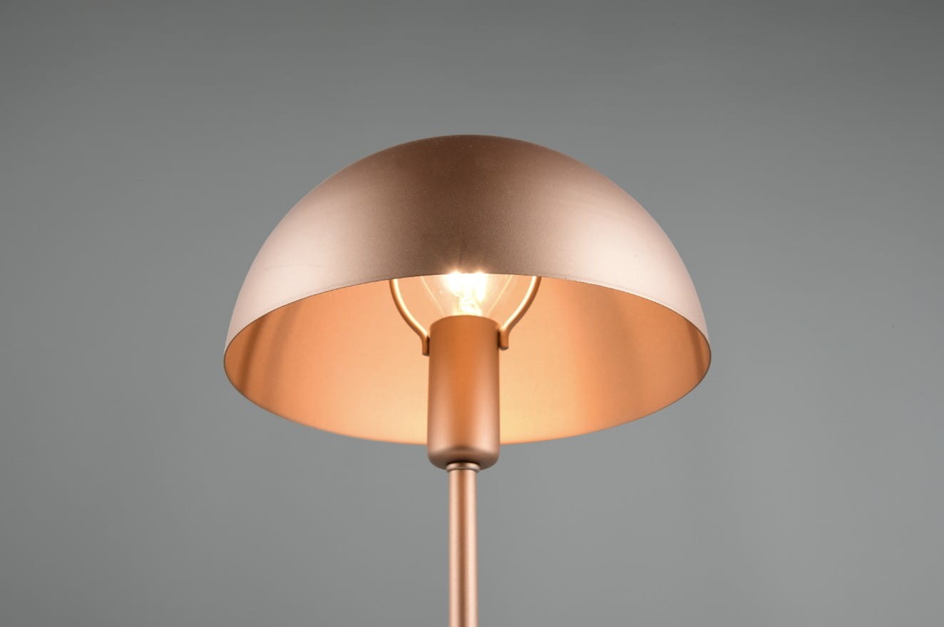 Lampa stołowa Nola w kolorze kawowym, z metalowym kloszem w kształcie półkuli. Widoczny gwint E27 z żarówką. Ujęcie z góry, pokazujące detal klosza oraz źródło światła. Prosta, nowoczesna forma.