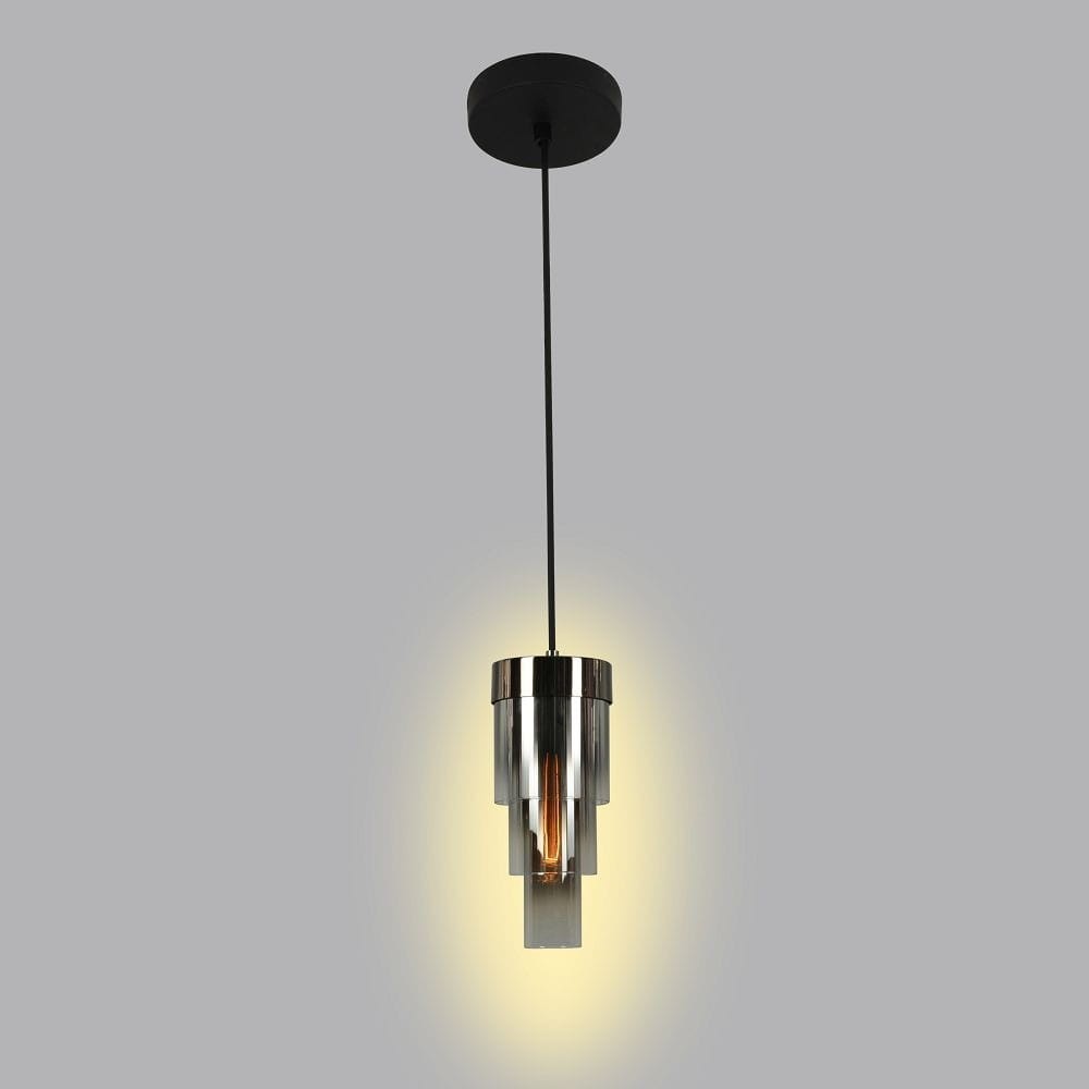 Lampa wisząca Grans 1xE27 w kolorze czarnym i chromowanym. Okrągła podsufitka, długi przewód. Szklany klosz w geometrycznym kształcie, emitujący ciepłe światło. Całość w minimalistycznym stylu, zawieszona na jednolitym tle.