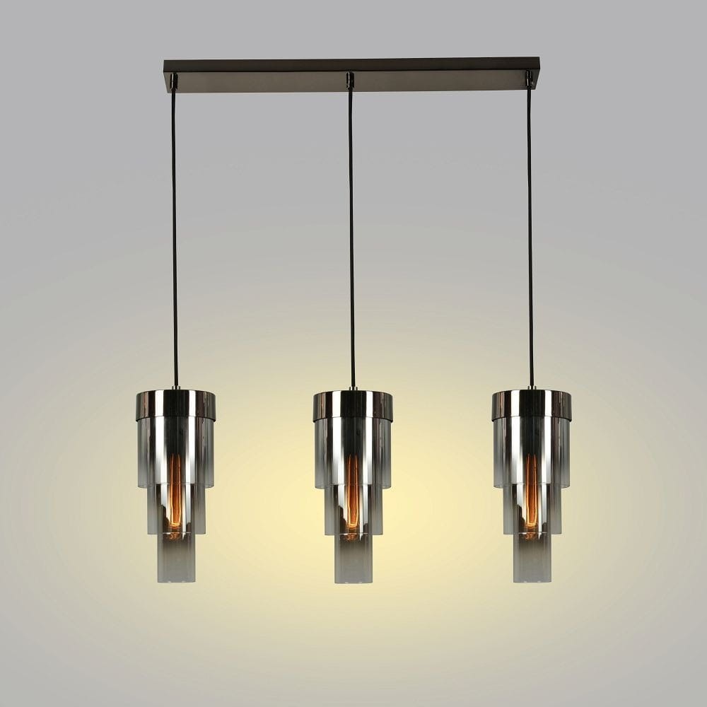 Lampa wisząca Grans z trzema kloszami, czarna z chromowanymi elementami. Klosze mają cylindryczny kształt i przezroczyste detale. Zawieszona na prostokątnej podstawie, emitują ciepłe światło, tworząc stylowy akcent w aranżacji wnętrza.