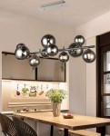 Lampa wisząca Sevilla w kolorze czarnym chrom z dymionymi kloszami, zawierająca 10 źródeł światła G9, zawieszona na prostokątnej, metalowej podstawie. Produkt umieszczony nad drewnianym stołem w nowoczesnej aranżacji kuchennej.