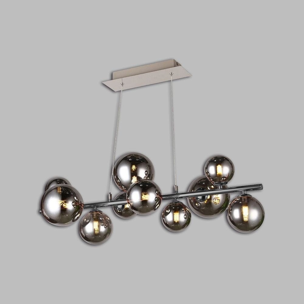 Lampa wisząca Sevilla z dziesięcioma źródłami światła G9, w kolorze czarnym i chromowanym. Posiada dymione, okrągłe klosze zawieszone na metalowej rurze, wiszącej na cienkich linkach, z prostokątnym wspornikiem sufitowym w jasnym kolorze.