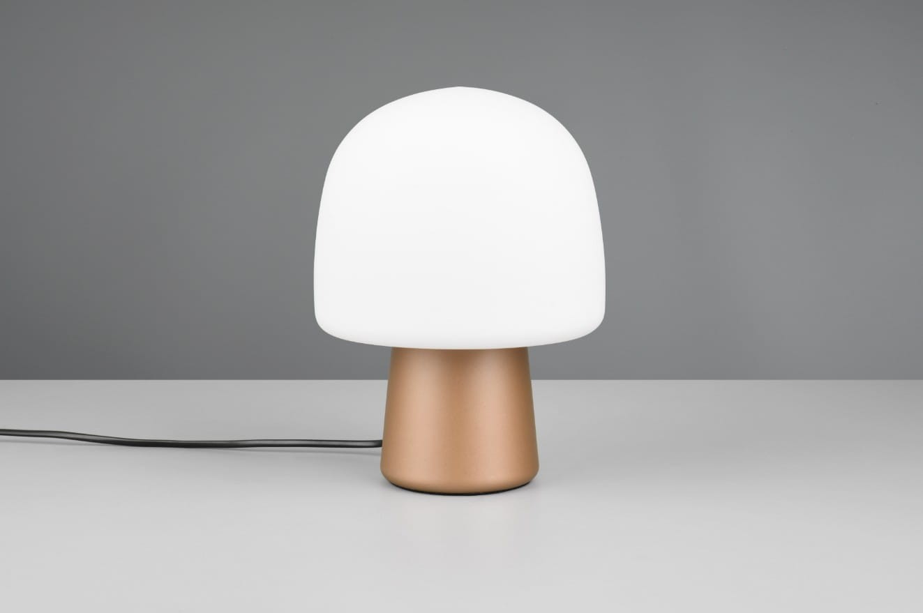 Brązowa lampa stołowa Steen z białym kloszem w kształcie grzyba, umieszczona na szarej powierzchni. Ujęcie frontalne, widoczny kabel zasilający. Klosz wykonany z matowego szkła, podstawa z metalicznego materiału.