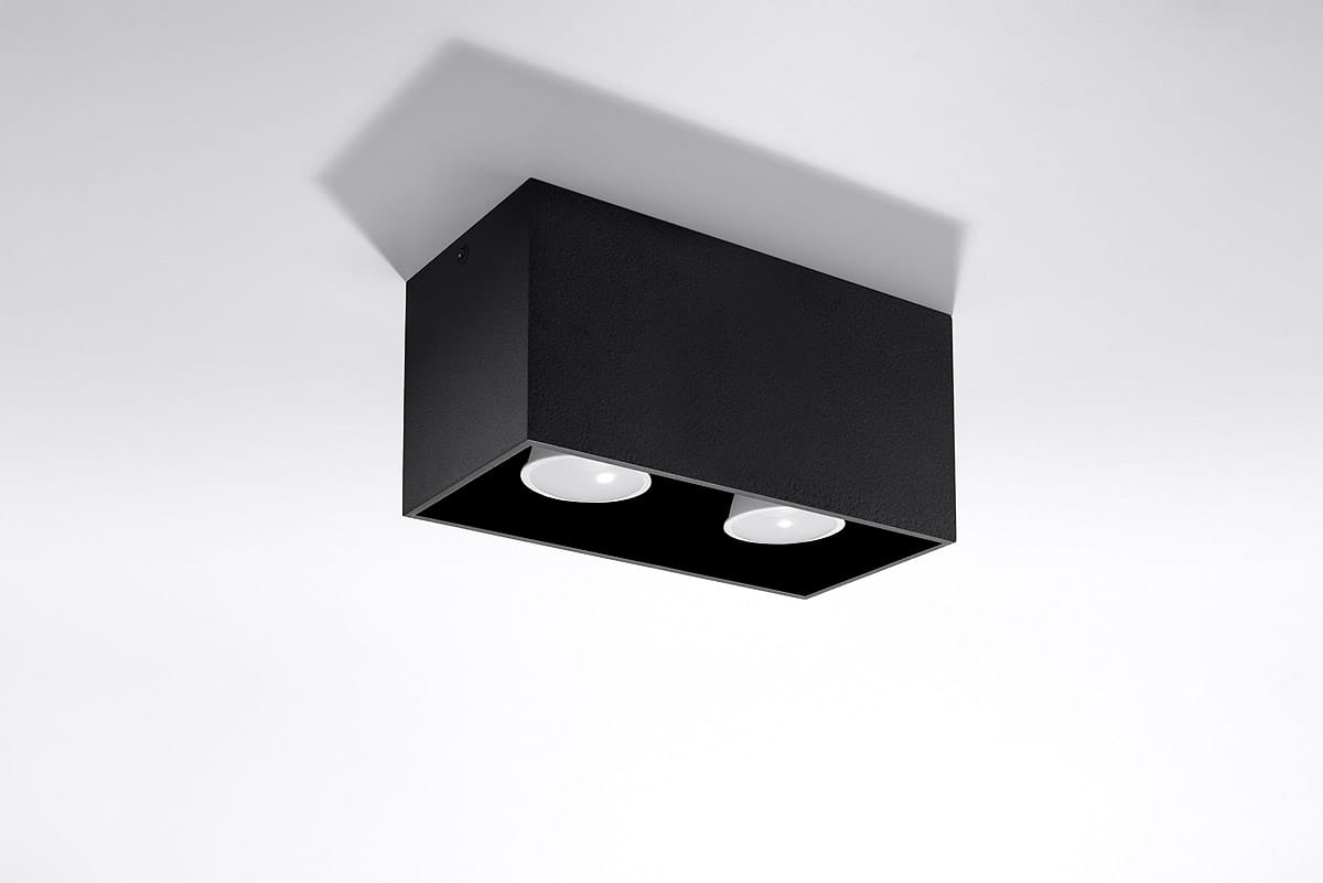Czarna lampa sufitowa Quad Maxi, 2-punktowa, z prostokątnym korpusem. Ujęcie z dołu, pokazujące dwa okrągłe klosze. Produkt zamontowany na białym tle, bez dodatkowych dekoracji. Świecące źródła światła widoczne wewnątrz lampy.