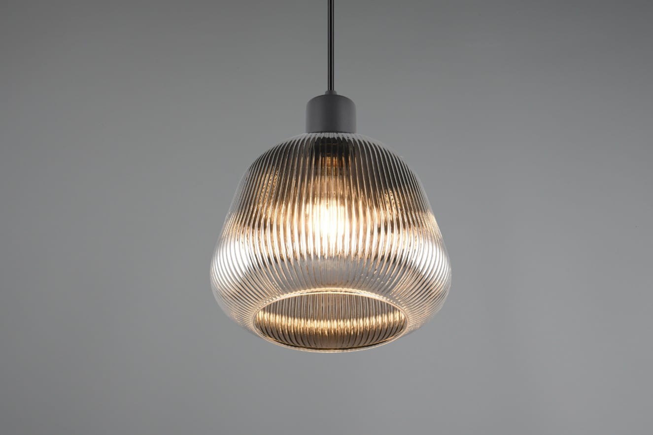 Lampa wisząca Tarifa z kloszem w kształcie dzwonu, w kolorze czarnym, z przezroczystym, żłobkowanym szkłem. Zawieszona na cienkim przewodzie, z widocznym miejscem na żarówkę E27. Klosz o szerokiej podstawie, idealna do nowoczesnych wnętrz.