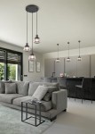 Czarna lampa wisząca Tarifa z jednym gniazdem E27, zawieszona na trzech linkach, z przezroczystym kloszem, umieszczona w nowoczesnej aranżacji wnętrza z szarym sofą i kuchnią w tle.