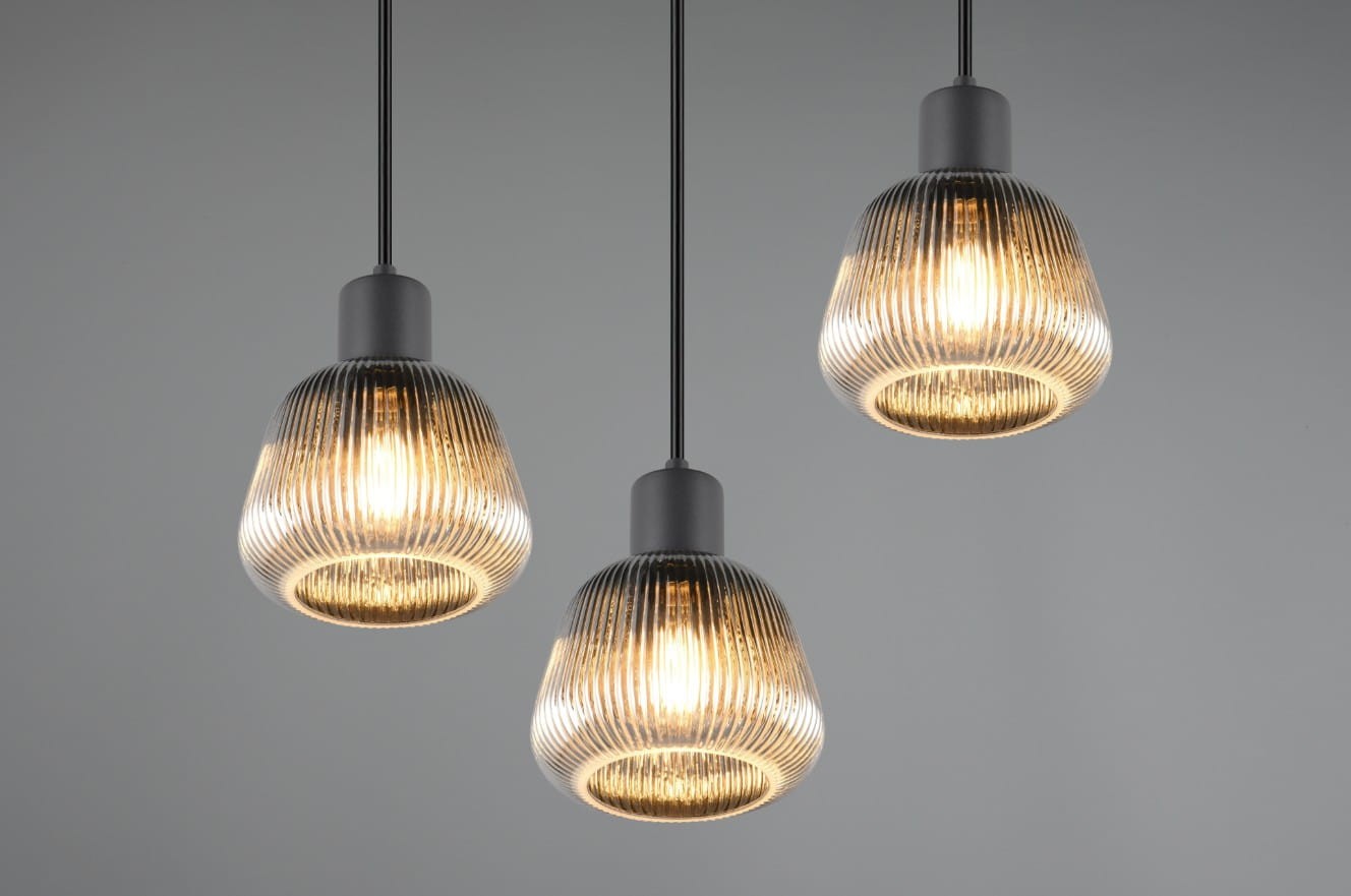 Lampa wisząca Tarifa z trzema żarówkami E27, w kolorze czarnym. Klosze w kształcie kulistym z przezroczystego szkła o teksturowanej powierzchni, zawieszone na cienkich, czarnych linkach. Oświetlenie w stylu nowoczesnym, na jednolitym tle.