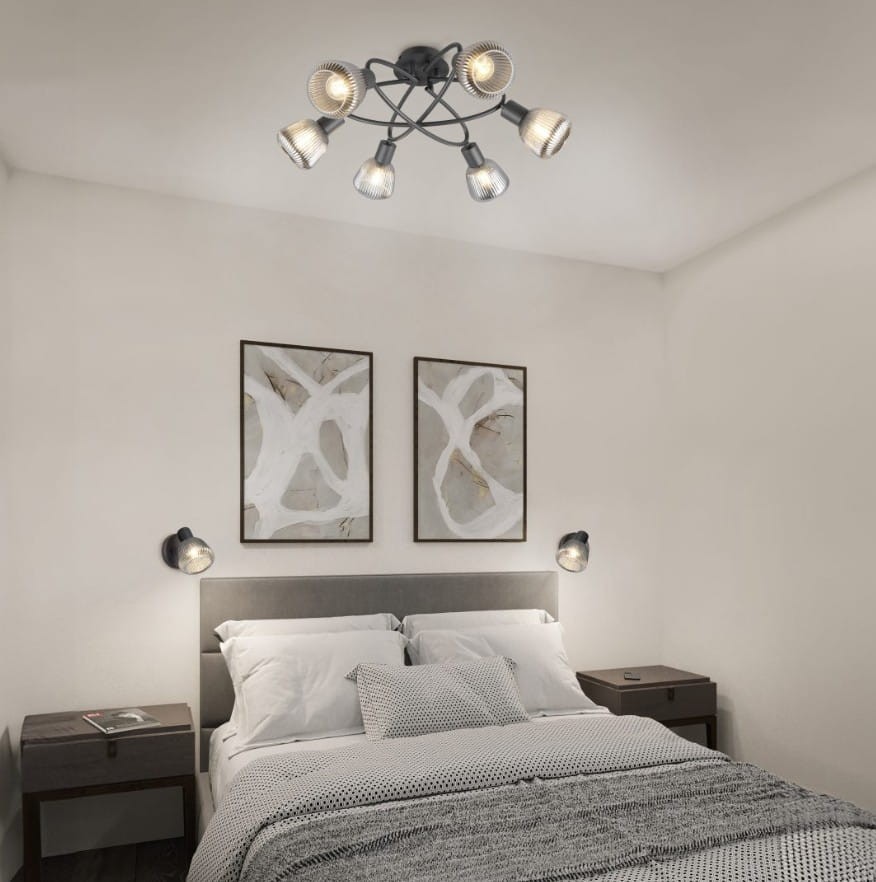 Lampa sufitowa Tarifa w kolorze czarnym z sześcioma miejscami na żarówki E14. Ujęcie z góry, zawieszona w sypialni, w otoczeniu dwóch obrazów na ścianie oraz lamp nocnych obok łóżka.