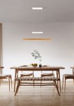 Lampa wisząca Trajan z trzema źródłami LED, w białej obudowie i jasnodrewnianym kloszu. Zawieszona nad drewnianym stołem w nowoczesnej jadalni, w otoczeniu krzeseł i dekoracyjnej rośliny w wazonie.
