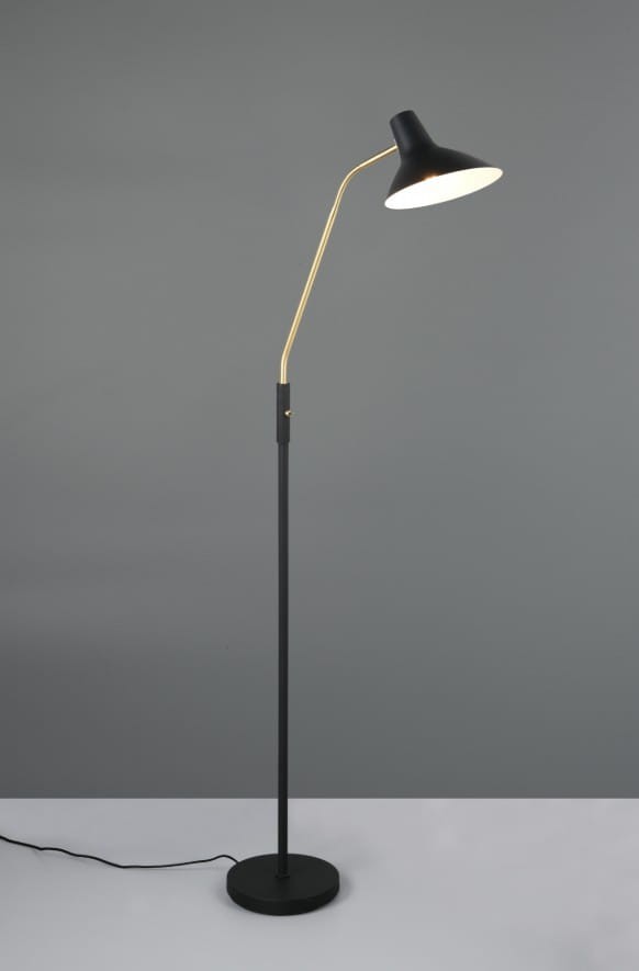 Lampa podłogowa Traveller 1xE27 w kolorze czarnym i złotym. Wygięta, metalowa konstrukcja z okrągłą podstawą. Klosz w kształcie stożka, zewnętrzna strona czarna, wewnętrzna biała. Kabel zasilający widoczny przy podstawie.
